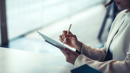 Close up of a businesswoman holding a pen working on a tablet at the office.