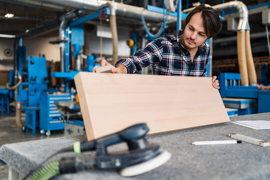 Industrial worker measuring wood plank while standing at industry
