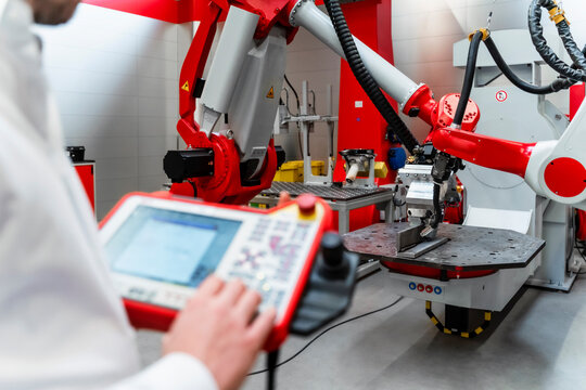 Male engineer with control examining robotics in factory