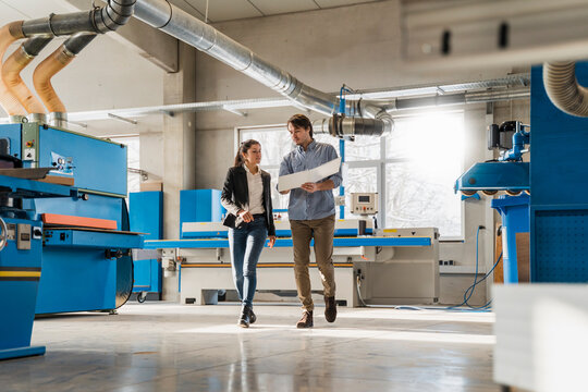 Business people having discussion over document while walking at industry