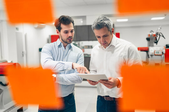 Male engineers seen through glass wall while discussing about business plans in factory