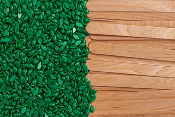 Green wax granules and a wooden depilation spatula. Top view close up - obrazy, fototapety, plakaty