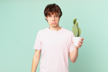 young man with a cactus feeling sad and whiney with an unhappy look and crying