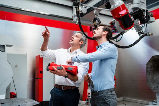 Male engineers examining robotics in factory