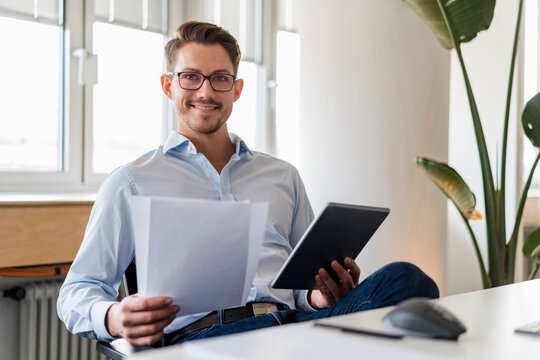 Confident businessman with document and digital tablet at office