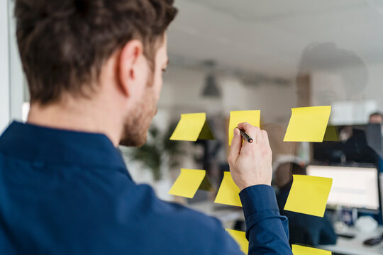 Male entrepreneur writing on adhesive note at office