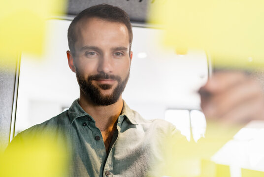 Male entrepreneur looking at adhesive note in office