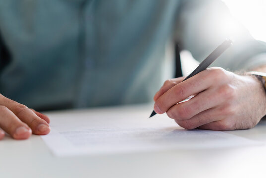 Businessman with pen filling document at office