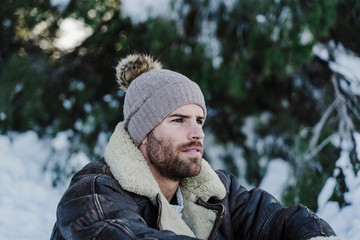 Young man in knit hat day dreaming during winter