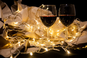 two glasses of red wine stand in a shining garland