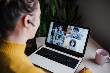 Young woman talking with friends over video conference on digital tablet while sitting at home