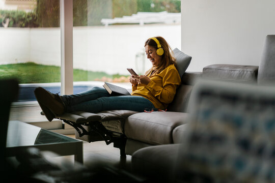 Mature Woman Listening Music While Sitting On Reclining Chair In Living Room