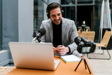 Smiling businessman making vlog on camera while sitting at cafe