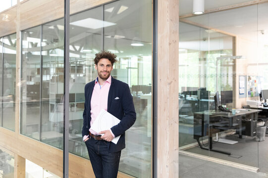 Male entrepreneur with document against glass wall at office