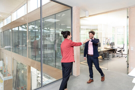 Male and female entrepreneurs giving fist bump at office