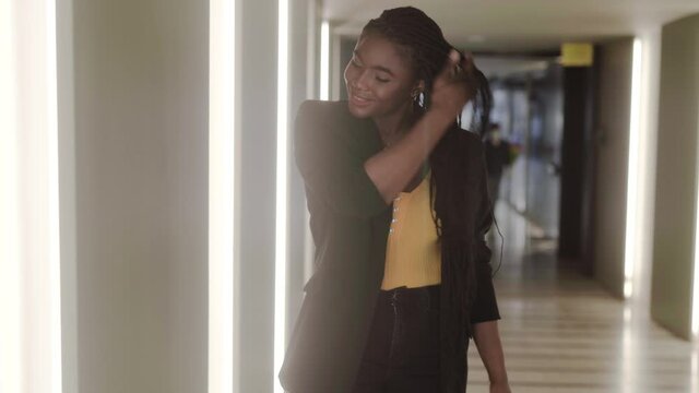 Stylish Black Woman Putting On Jacket While Walking In Hall