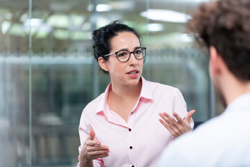 Female entrepreneur gesturing while talking to male colleague in office