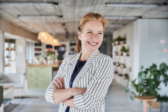 Smiling mature woman with arms crossed at home
