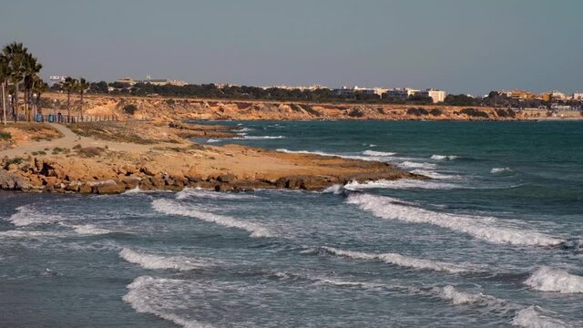 Slow motion footage of Rocky coast of Flamenco beach in the Orihuela Costa. Surf Mediterranean Sea, winter tropical climate sunny day. Province of Alicante, Costa Blanca, Spain
