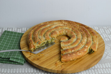Greek cheese spinach pie, spanakopita on the wooden board and green kitchen cloth