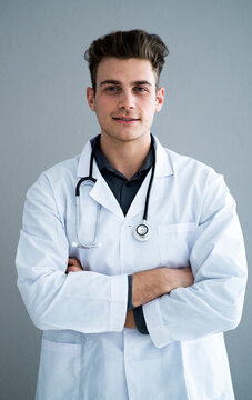 Male handsome doctor with arms crossed against gray wall