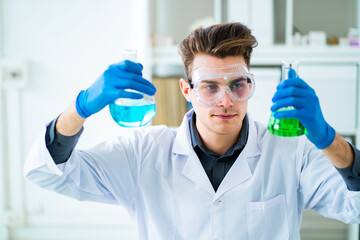 Male scientist holding chemical flasks in laboratory