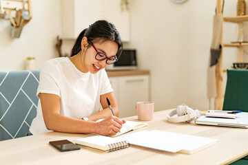 Smiling woman writing in book at home