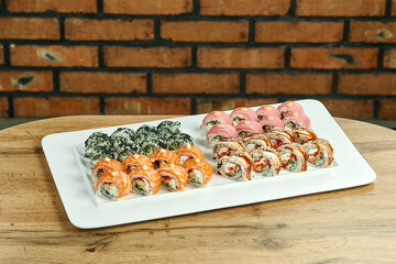 sushi set with salmon, eel, tuna and caviar on a white plate on a wooden background with a brown brick background