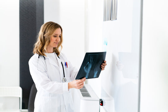 Blond female radiologist examining X-ray at medical clinic