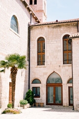 Glass doors and windows in the Monastery of St. Franz in Sibenik against the background of blue sky and green palm tree
