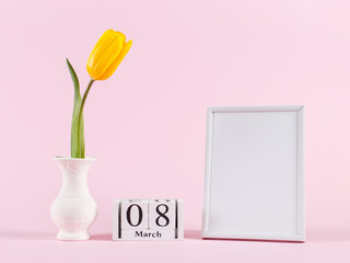 Tulip in vase, photo frame and calendar March 8 on a pink table. Copy space.