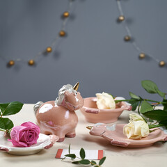 kitchen set with a figurine of a uniform and plates decorated with pink and yellow roses on a wooden background with a gray background