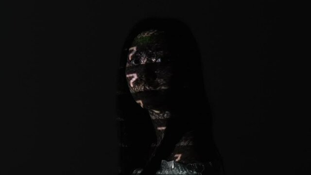 System error. Memory loss. Mental disorder. Amnesia brain damage. Confused puzzled glitched Asian woman face in dark analog VHS noise motion projector light isolated on black.