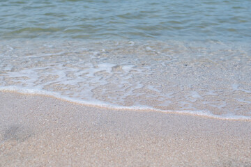 Wide view of ocean waves and white bubbles, lapping onto the beach.