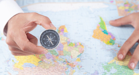Fototapeta na wymiar Male hand showing compass on the world map background.