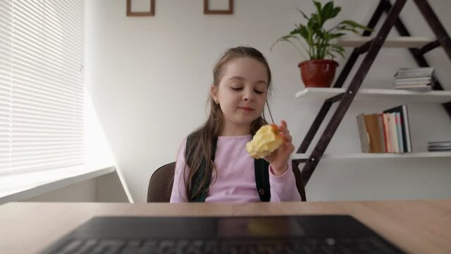 Tired of the lessons, the student eats a large juicy fresh apple for lunch. A useful fruit for the health of schoolchildren. Snack at home with distance learning. web camera view