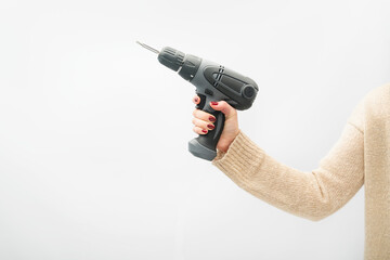 Female hand holds screwdriver drill. White background.