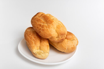 Profiteroles, puffs, popovers, eclaires on white saucer against. White background