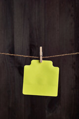 Blank yellow paper card hang with clothespin on rope. Copy space. Place for your text. Vertical frame