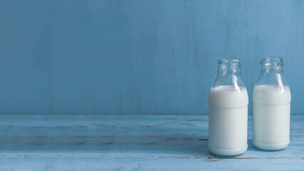 Milk bottles for Jewish holiday Shavuot on blue wooden background with copy space.