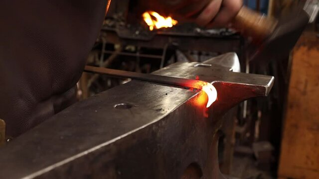 Blacksmith forging a hinge eye by hand at the anvil