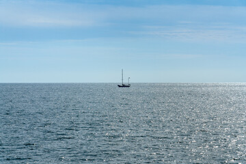 Wide ocean view with a single sailboat at the horizon