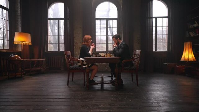 Two chess players man and woman play chess. Debut Accepted Queen's Gambit, King's Gambit, Philidor's Defense. Cinematic filming of a chess game. Antique chess board. This shot can be used for films