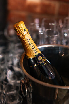 PERM, RUSSIA SEPTEMBER 5, 2020: Bottle of luxury champagne Moet and Chandon Imperial in a bucket of ice. Chilled sparkling wine at a dinner party against a dark background. champagne glasses nearby
