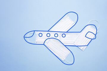 Airplane model made of protective masks with an outlined outline on a blue background. Safe travel by plane concept. New normal concept.