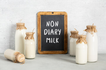 Vegan non dairy plant based milk in bottles on light background. Alternative lactose free milk...