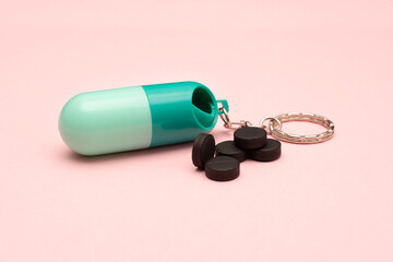 Travel pill box. Pill shape. The use of tablets in doses. Keep your health. Activated carbon on a colored background.
