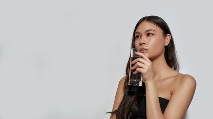 Cute young asian girl drinking water from glass - obrazy, fototapety, plakaty