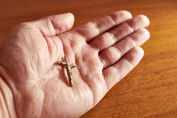 The cross with the crucifixion of Jesus Christ lies in a man's palm