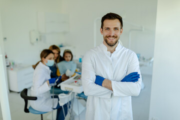 Female dentist standing with his hands crossed, wearing glows and white coat and looking at camera.